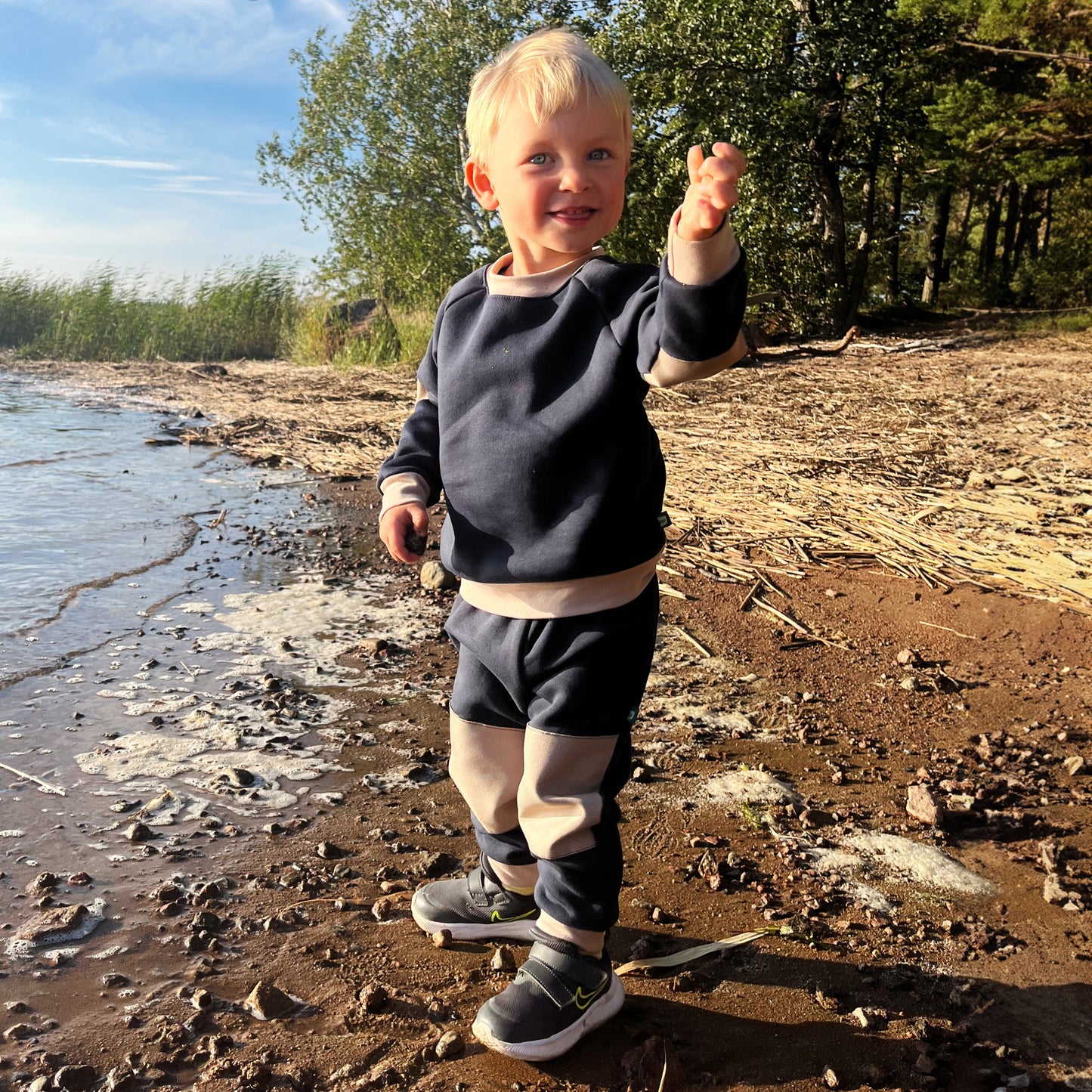 Poika seisoo rannalla Vainion housut ja pitkähihainen paita päällään